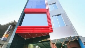 A multi-story building with a prominent red and blue facade, large windows, and a clear sky. - Hotel Singh Palace (Purnia)