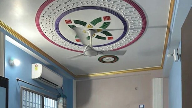 A bedroom with a bed, a chair, a radiator, and a ceiling fan. - Hotel Singh Palace (Purnia)