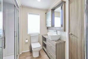 Ein Badezimmer mit Toilette, Waschbecken, Spiegel und Dusche.