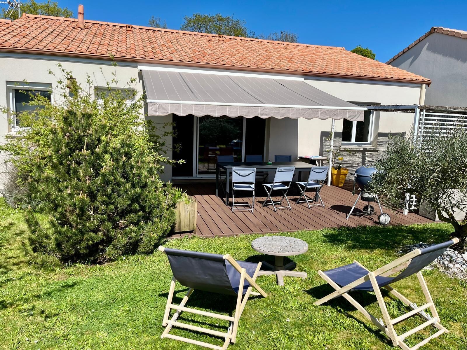 Une terrasse avec des meubles d’extérieur, un barbecue et un espace abrité.