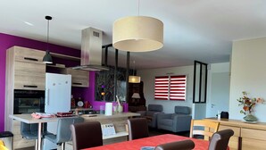Eine moderne Küche mit Essbereich, einem roten Tisch und einem grauen Sofa.