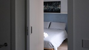 Une chambre à coucher avec un lit, un tableau au mur et une porte.