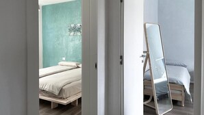 Une chambre à coucher avec un lit, un miroir et un mur d’accent de couleur turquoise.