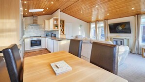 Eine moderne Küche mit weißen Schränken, einer Holzbalkendecke und einem Essbereich mit Tisch und Stühlen.