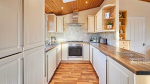 Eine Küche mit weißen Schränken, Holzboden und einer integrierten Backofen sowie einer Arbeitsplatte aus Holz.