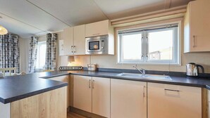 A modern kitchen with a built-in microwave, a sink, and a window with a view. - Host & Stay | ORC02 Hidden Gem Lodge (Amotherby)