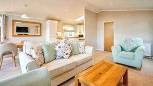 A living room with a sofa, a coffee table, and a light blue armchair. - Host & Stay | GRE06 Deneb Lodge (Amotherby)