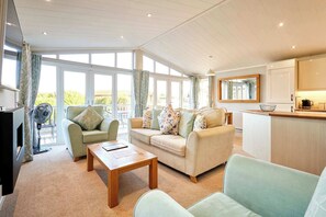 A spacious living area with a sofa set, a coffee table, and a dining area with a kitchen counter. - Host & Stay | GRE06 Deneb Lodge (Amotherby)