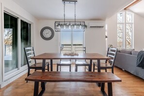Un coin repas avec une table et des chaises en bois, un luminaire suspendu et une vue par la fenêtre.