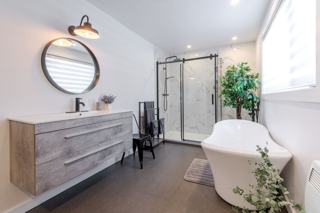 A modern bathroom with a freestanding bathtub, a glass-enclosed shower, and a vanity with a mirror and towel rack.