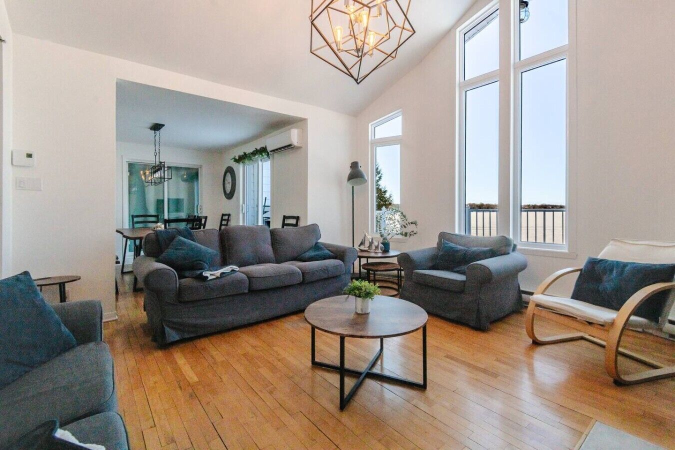 A spacious living room with a grey sofa set, a round coffee table, and a wooden floor.