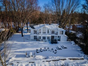 Un grand bâtiment blanc doté de nombreux balcons, entouré d’un paysage enneigé et d’arbres sans feuilles.