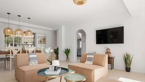 Un salon moderne avec deux canapés, une table basse et un téléviseur fixé au mur.