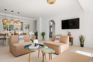 Un salon moderne avec deux canapés, une table basse et un téléviseur fixé au mur.