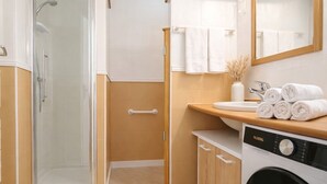 Ein Badezimmer mit Dusche, Waschbecken, Handtuchhalter und Waschmaschine.