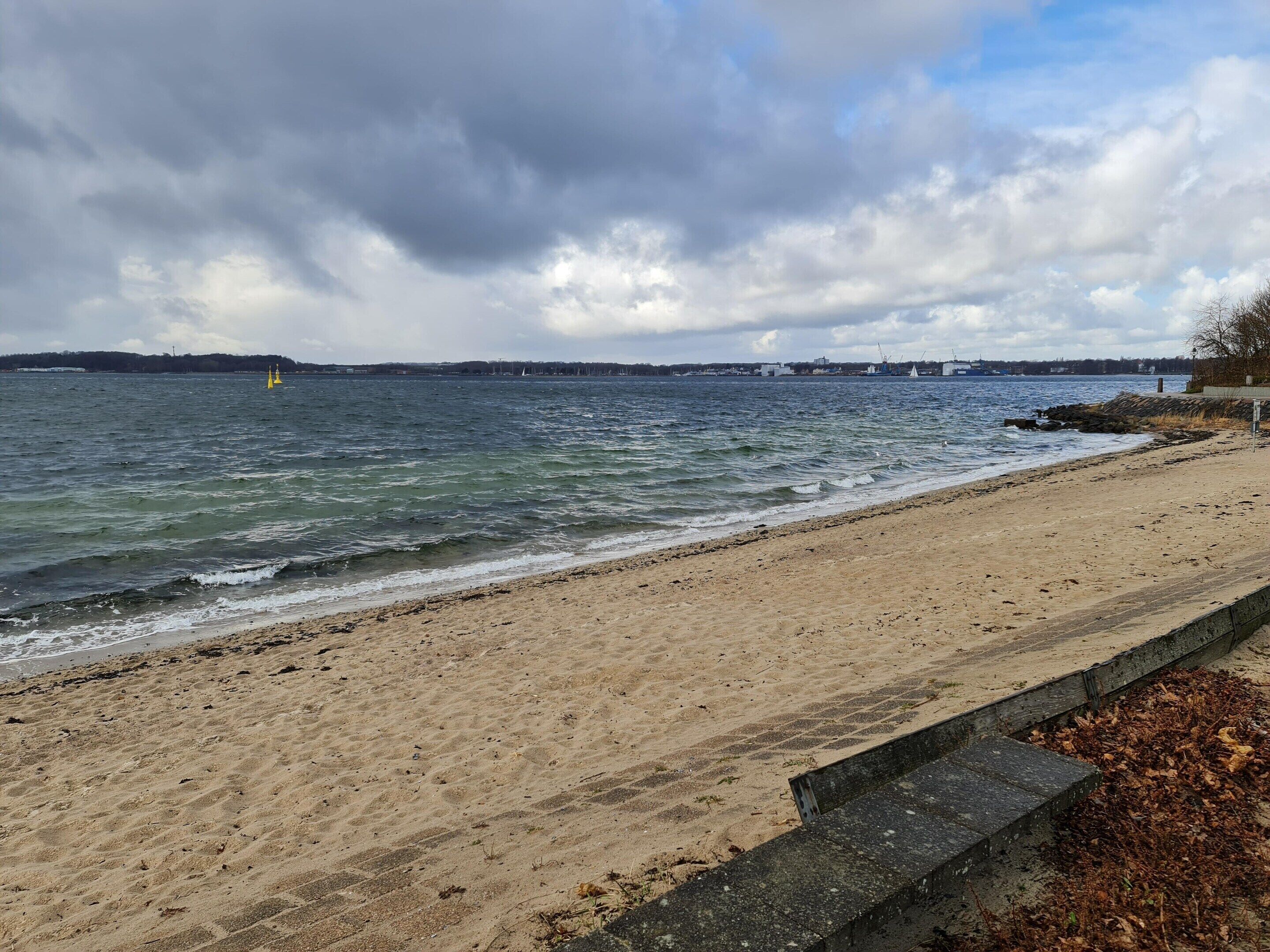 A sandy beach with a wooden walkway leading to the water.