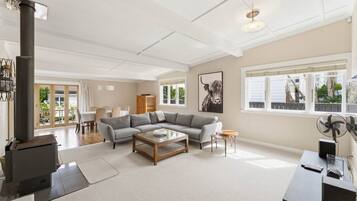 A spacious living room with a large gray sectional sofa, a wooden coffee table, a fireplace, and a dining area with a table and chairs.