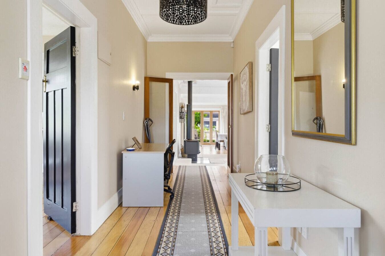 A hallway with a white console table, a mirror, and a door with a black frame.