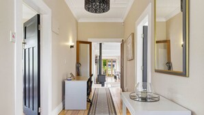 A hallway with a white console table, a mirror, and a door with a black frame. - 1920s Character Gem in Sandringham | Garden & Deck (Auckland Central)