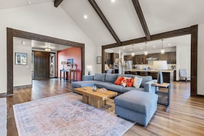A spacious living area with a large sectional sofa, a wooden coffee table, and a patterned rug.