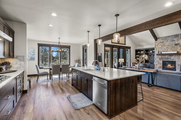 Una cocina moderna con una isla central, suelo de madera y chimenea de piedra.