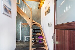 A wooden staircase leading to a room with a bed, a chair, and a coat rack. - Spacious Family-Friendly Apartment with Private Terrace, Home Office & Fireplace (Wangerland)