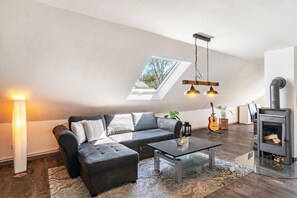 Een woonkamer in loftstijl met een bank, een poef, een glazen salontafel en een open haard.
