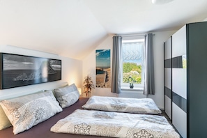 Een moderne slaapkamer met een bed, een groot raam en kunstwerken aan de wanden.