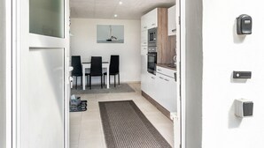 Eine moderne Küche mit weißen Schränken, einem eingebauten Backofen und einem Essbereich mit Tisch und Stühlen.
