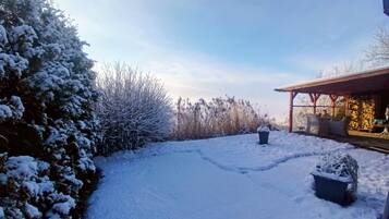 Ein mit Schnee bedeckter Garten mit einer Steinmauer und einer Holzhütte.