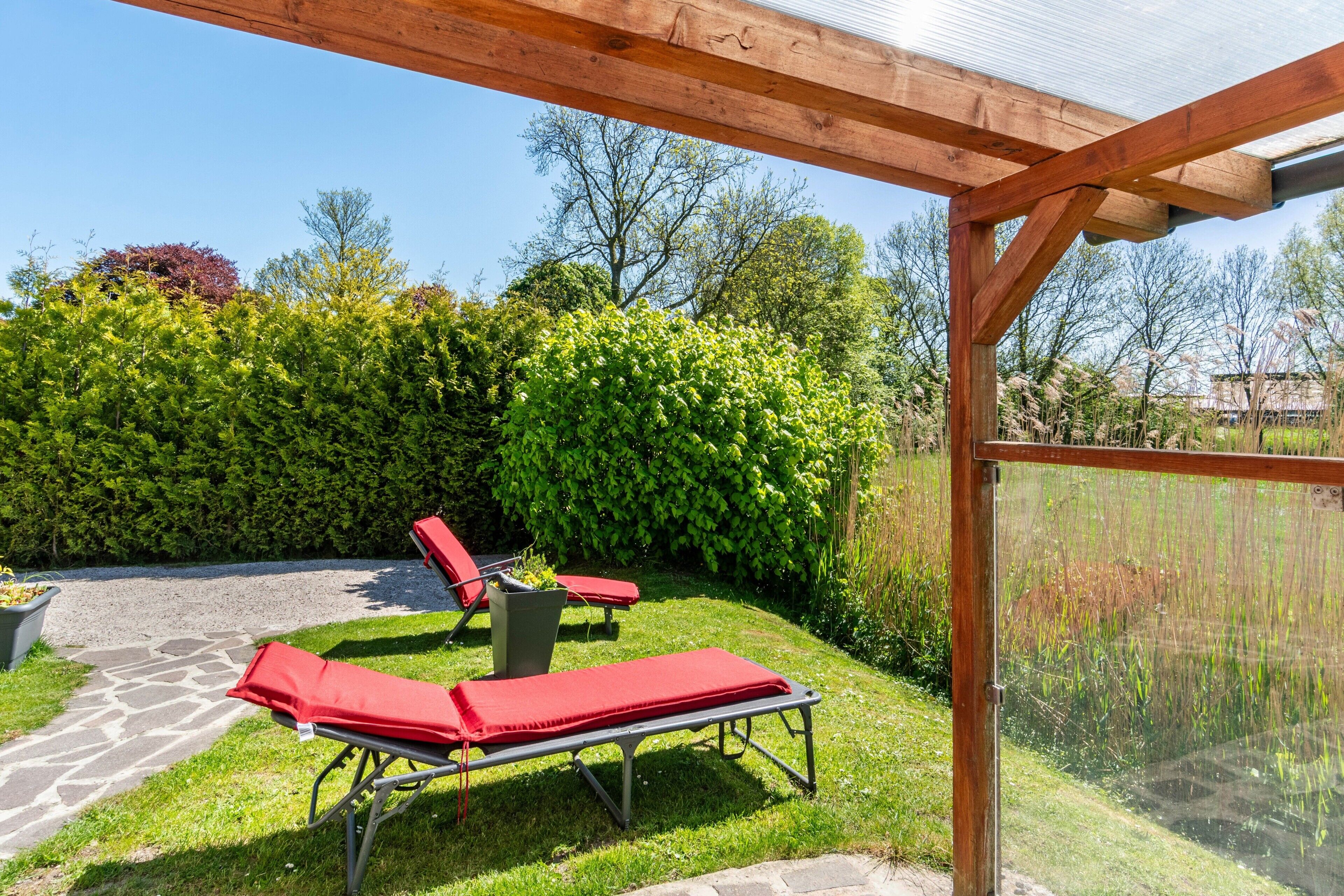 A covered outdoor area with lounge chairs and a stone pathway.