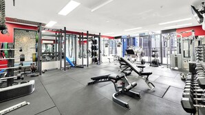 Ett gym med olika typer av träningsredskap, en bänkpress och ställ för vikter.