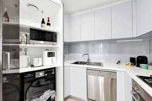 A modern kitchen with a dishwasher, microwave, and oven. -  FREE Private Parking | Walk to Crown & MCEC | Fast Tram to MCG & Marvel Stadium (South Melbourne)
