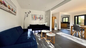 Una sala de estar moderna con un sofá azul oscuro, una mesa de centro y un cuadro en la pared.