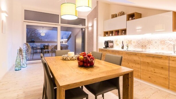 Una cocina moderna con armarios de madera, una mesa de comedor con sillas y una cesta de frutas.