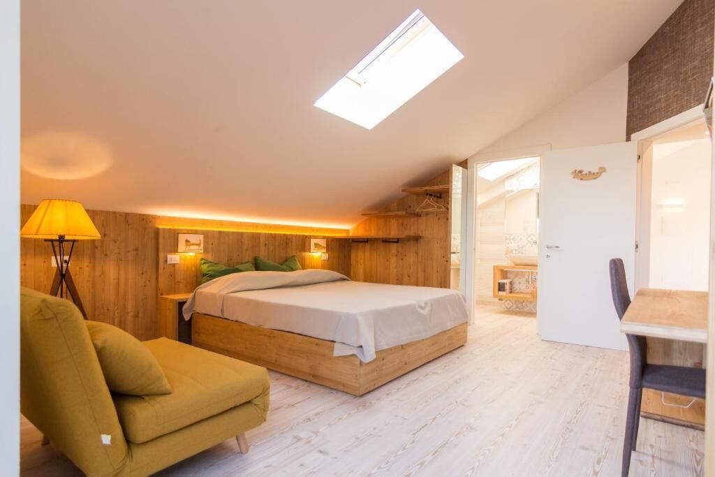Un dormitorio con cama, una silla, un escritorio y un armario.