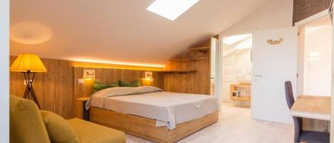 Un dormitorio con cama, una silla, un escritorio y un armario.