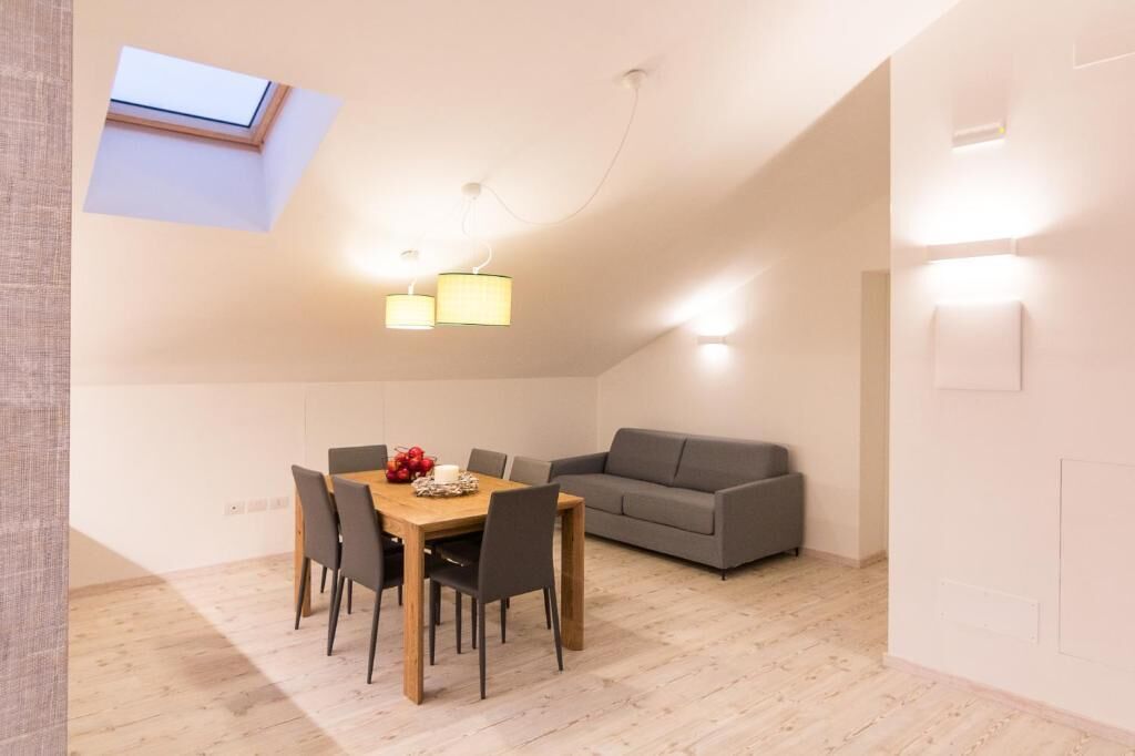 A modern interior with a dining table, chairs, a grey sofa, and a skylight.