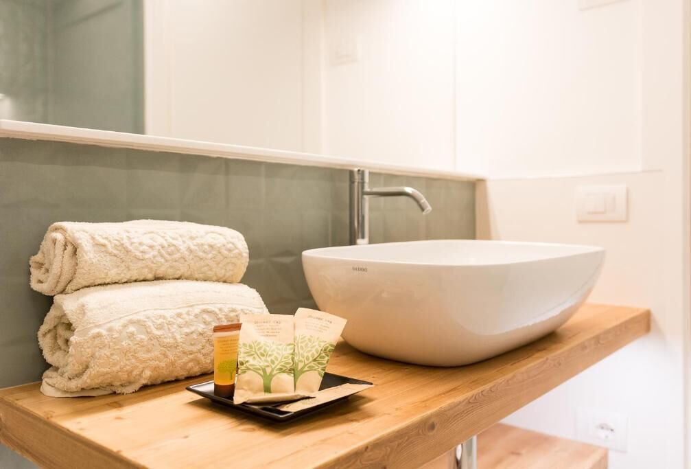 A bathroom with a white sink, a towel, and a tray with toiletries.