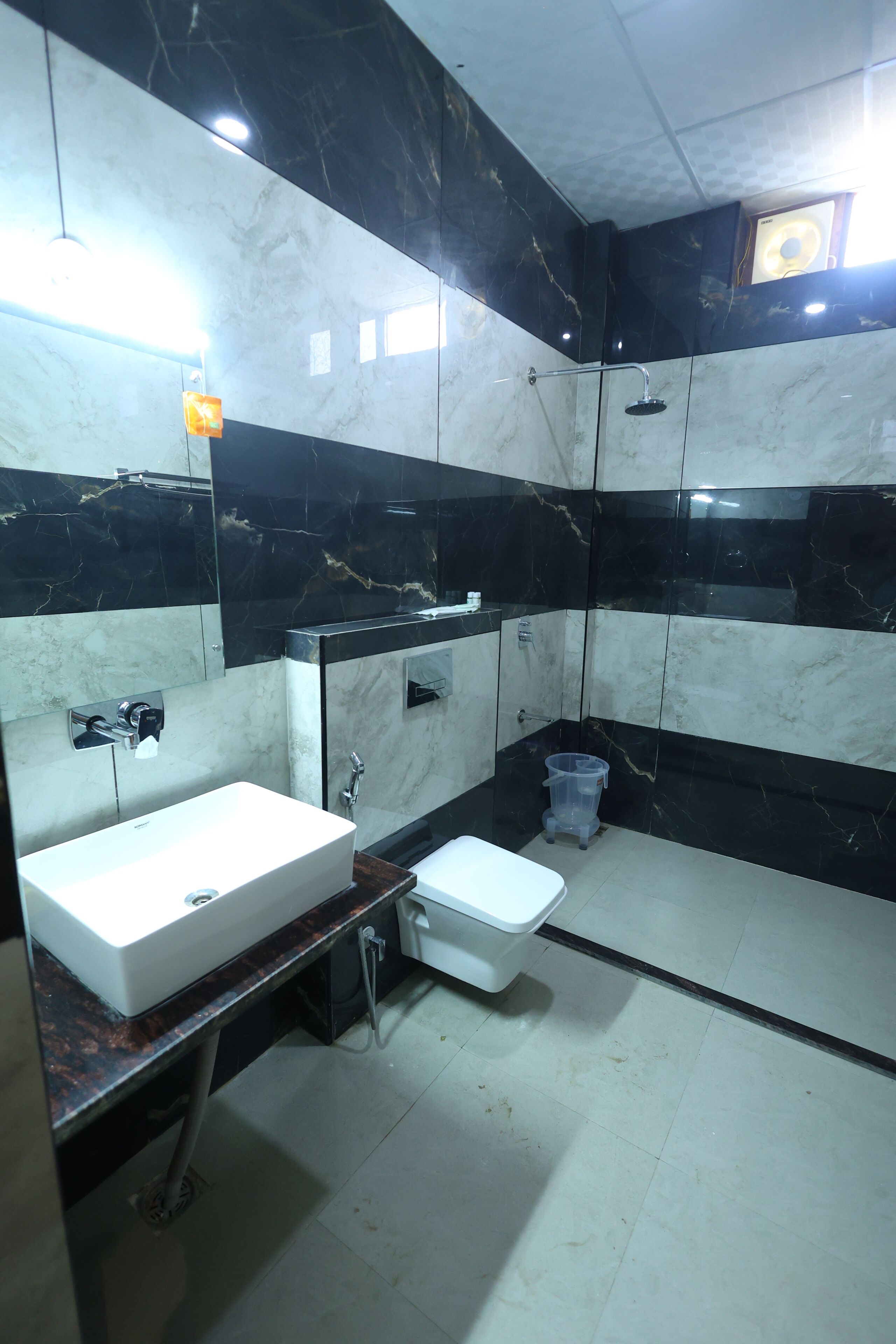 Un baño con lavamanos blanco, inodoro, ducha y cubo de basura.