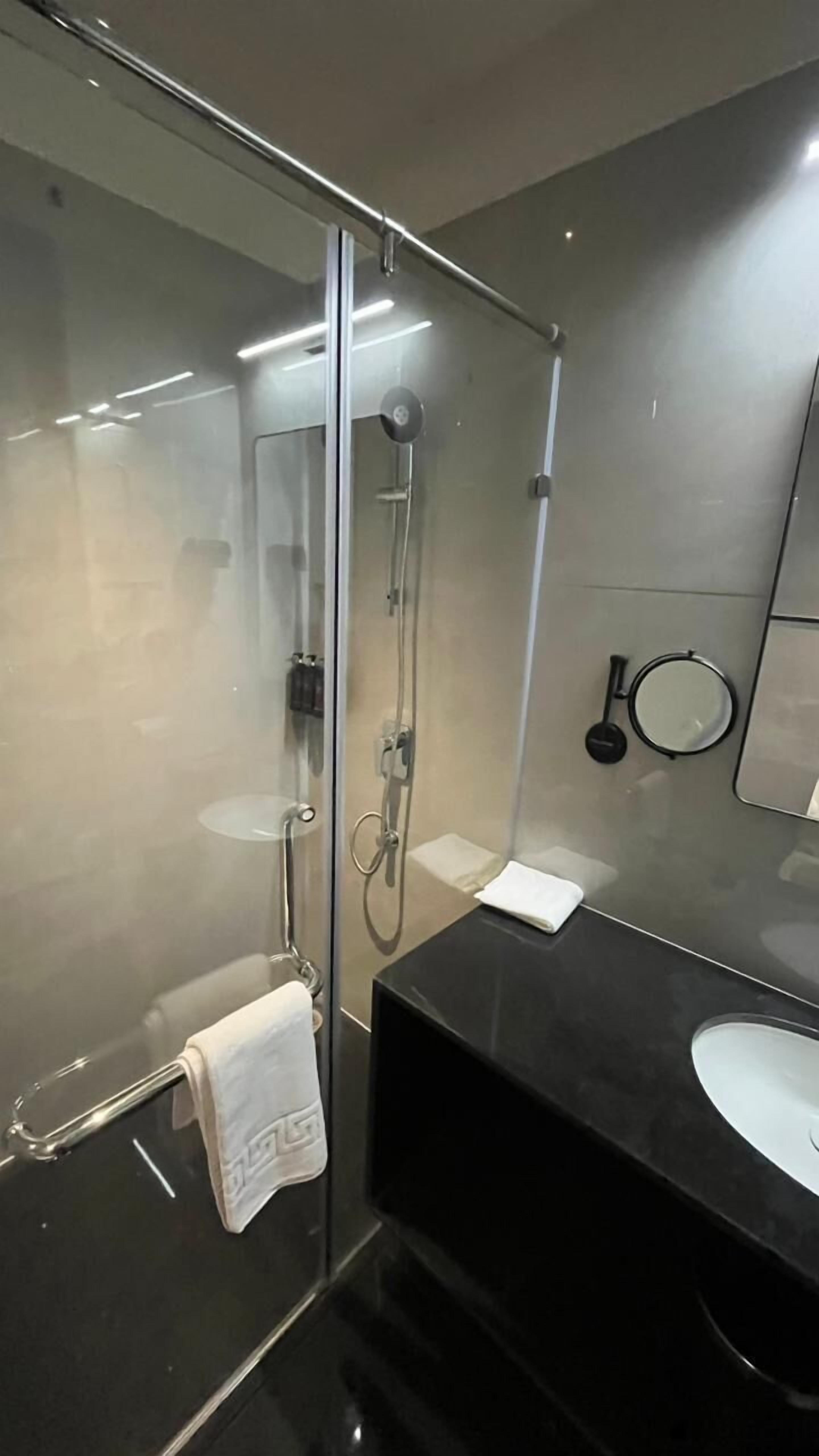 A modern bathroom with a glass-enclosed shower, a black vanity, and a mirror.