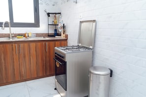 Une cuisine équipée d’une cuisinière à gaz, d’un four et d’une poubelle.