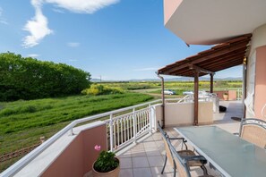 Ein Balkon mit Tisch und Stühlen, einem Blumentopf und Blick auf eine grüne Landschaft.