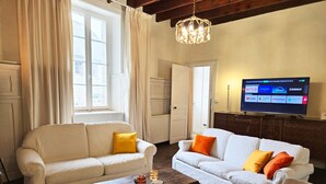 A living room with two white sofas, a wooden coffee table, and a television displaying streaming services. - Bernard & Bernadette, la familiale près de l'étang (Châtelaudren-Plouagat)