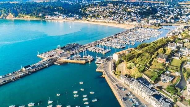 An aerial view of a coastal town with a marina, residential areas, and a prominent church. - Bernard & Bernadette, la familiale près de l'étang (Châtelaudren-Plouagat)