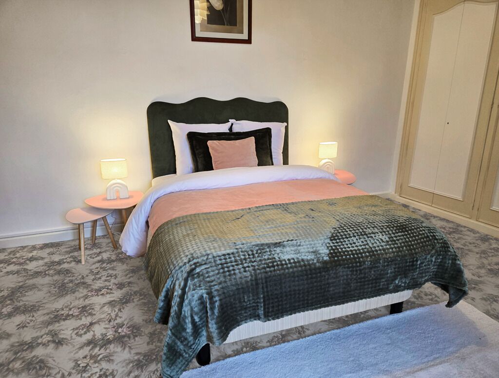Une chambre à coucher comprenant un lit, deux tables de chevet, une commode, une lampe fixée au mur et une armoire.