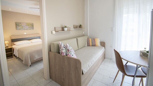 Una habitación de hotel moderna con una cama, un sofá, una mesa de comedor y una silla.