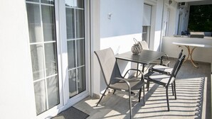Un balcón con una mesa y sillas, un pequeño objeto decorativo sobre la mesa y vistas al exterior.