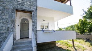 Un edificio de dos pisos con fachada de piedra, un balcón y una ventana pequeña.