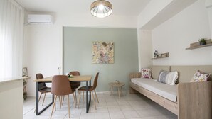 A modern living space with a dining area, a sofa, a small round table, and a hanging light fixture. - Forest View Apartment 1 by RentalsPro (Fourka)